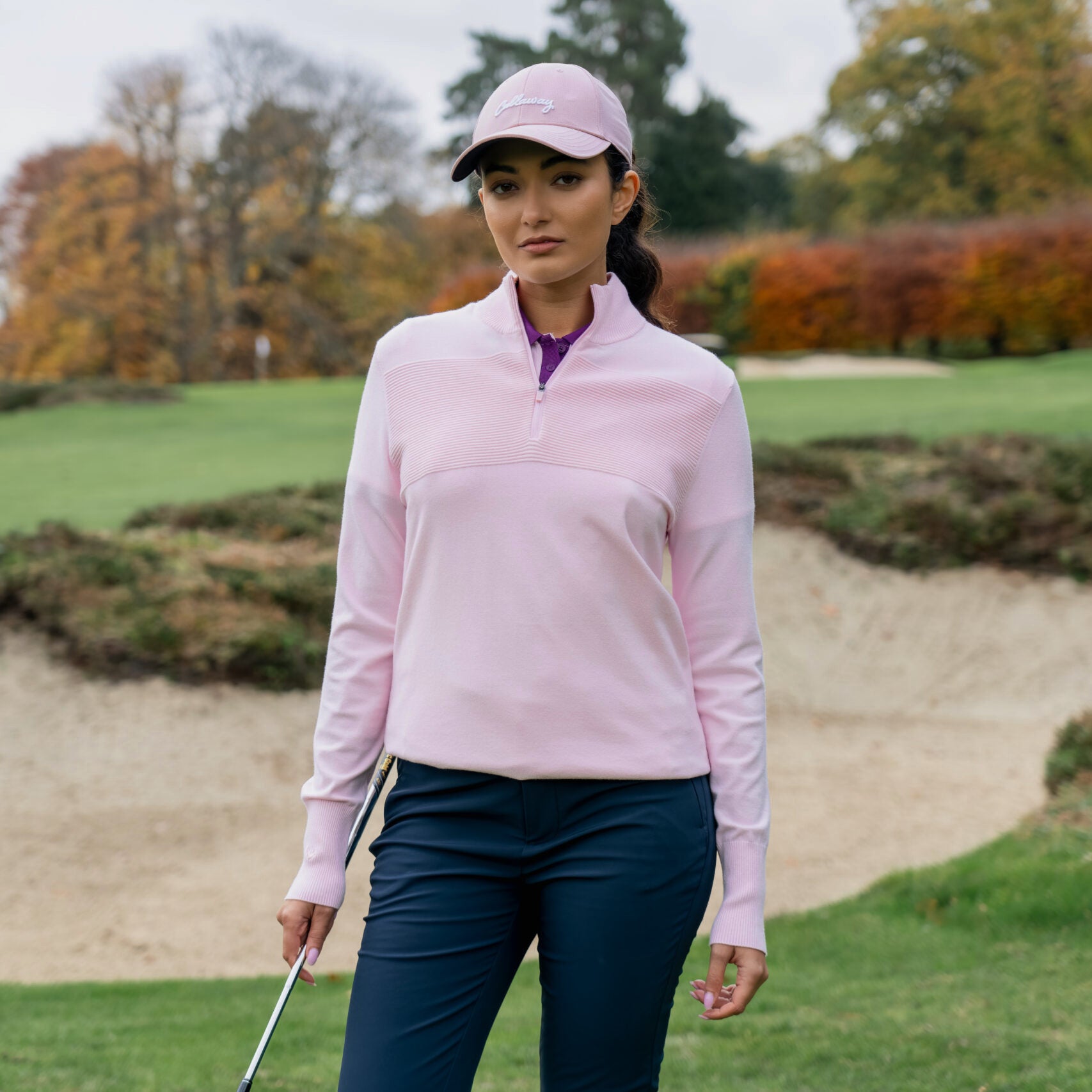 Kvinnlig golfare bär Callaway Soft Stretch Zip-Neck Sweater i Cherry Blossom på golfbanan